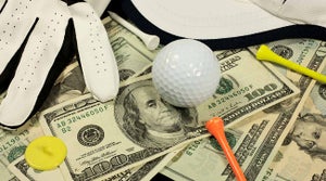 Golf ball and tee on stack of money.