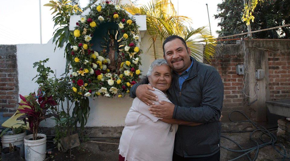 Mexican golf star José de Jesús Rodriguez stands with his mother, Josefina Martinez Aguilar, in front the Virgin de Guadalupe shrine at her home. His mother is extremely important to Rodriguez. He expresses gratitude to her for everything he has become and frequently talks about how deeply he missed her when he lived as an immigrant for years in the United States, before becoming a golf star.