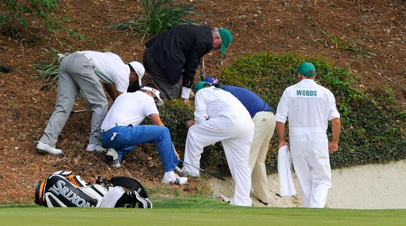 Caddies and officials search for a golf ball at the Masters.