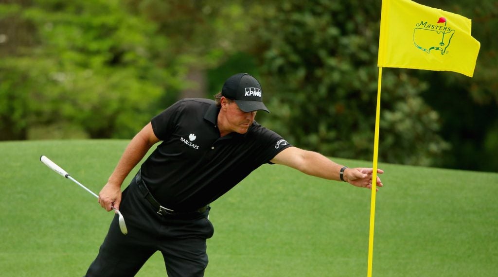 Phil Mickelson tends a flagstick during the final round of the 2015 Masters