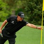 Phil Mickelson tends a flagstick during the final round of the 2015 Masters