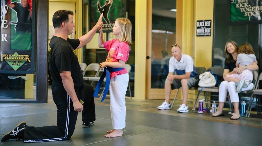 Amelia works with her martial arts instructor as her parents and sister look on.