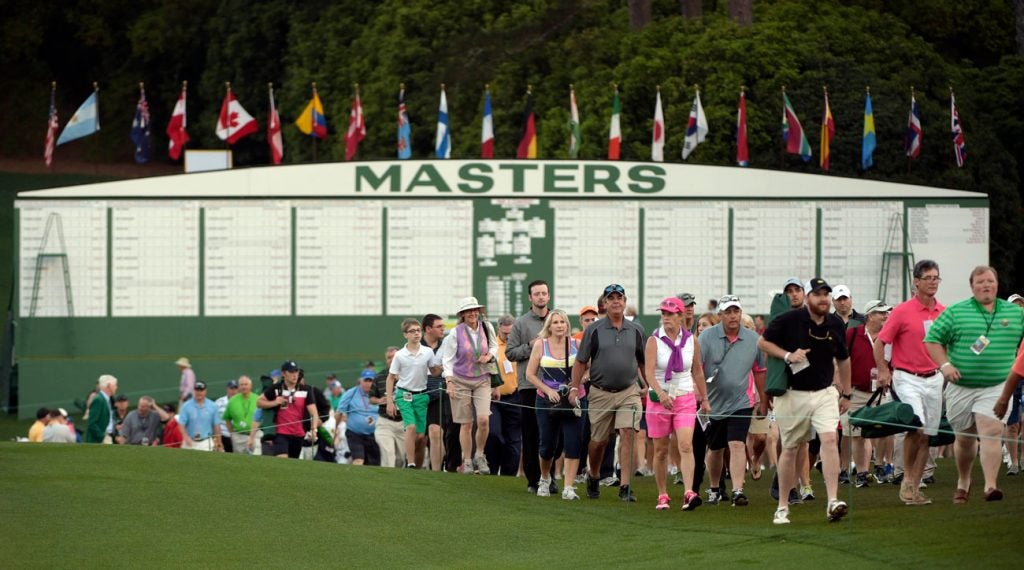 Tournament patrons line the walkway in front of the Masters leaderboard.