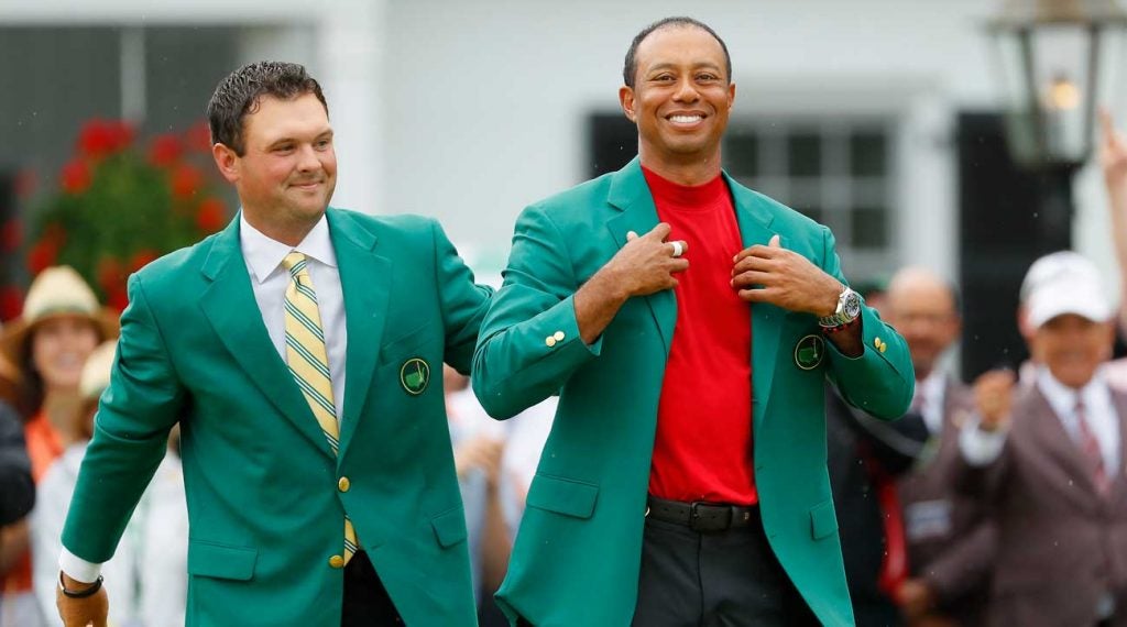 Patrick Reed helps fit Tiger Woods with a fifth green jacket.