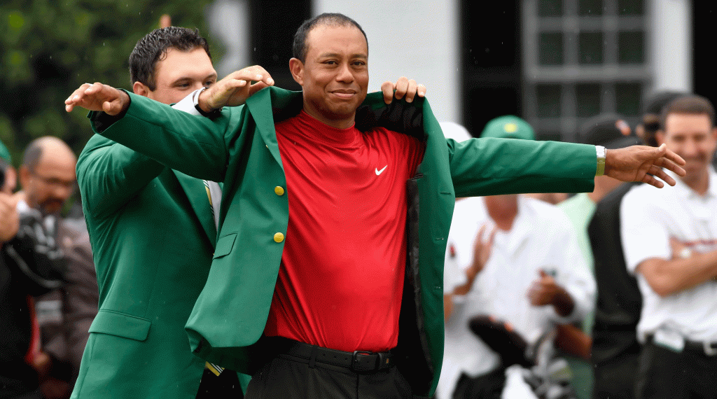 Patrick Reed slips the green jacket on to Tiger Woods.