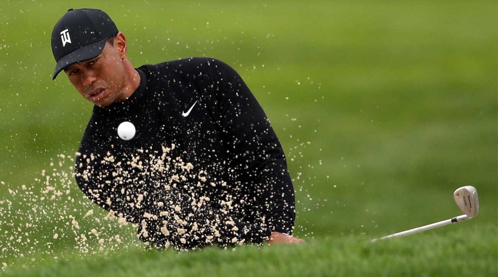 Tiger Woods blasts out of a bunker during a practice round at Bethpage Black on Tuesday.