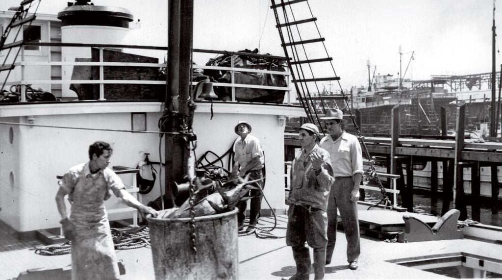 Al Santos (far right), conducting business on his fishing boat.