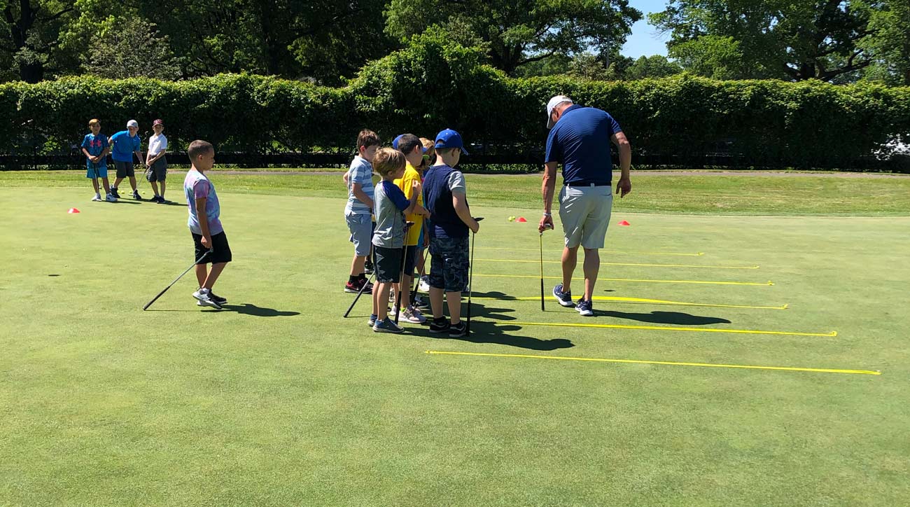 A group of students watch one of the golf instructors explain a putting game at the Brooklyn junior golf center in Dyker Heights.