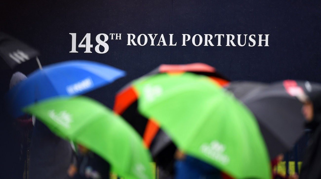 Golf fans converge with umbrellas due to cold, windy and wet weather during a practice round of The Open Championship golf tournament at Royal Portrush Golf Club.