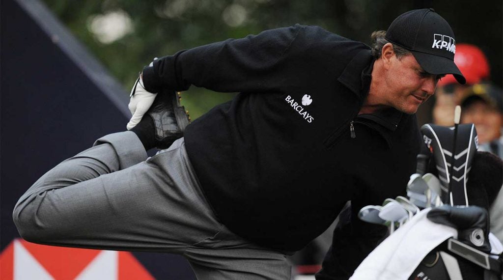 Phil Mickelson stretches his quadriceps before teeing off.