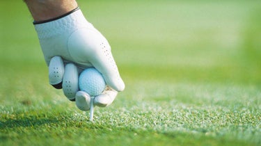 A golfer tees up a golf ball.