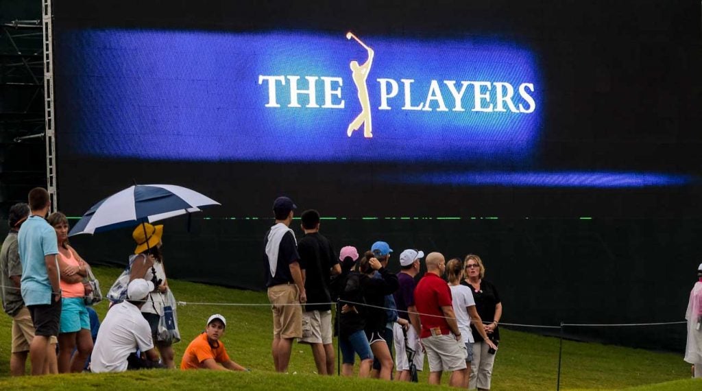 Spectators stand underneath a video screen at the 2014 Players Championship.