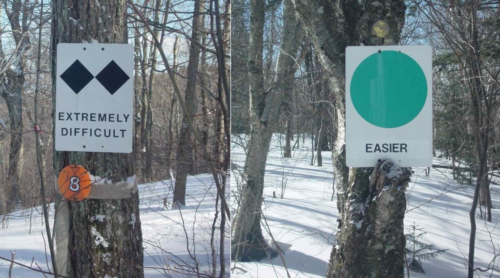 A black diamond and green circle sign at a ski slope.
