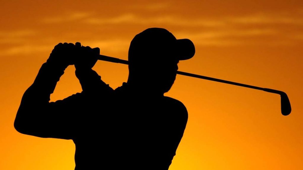 Golfer silhouetted at sunset