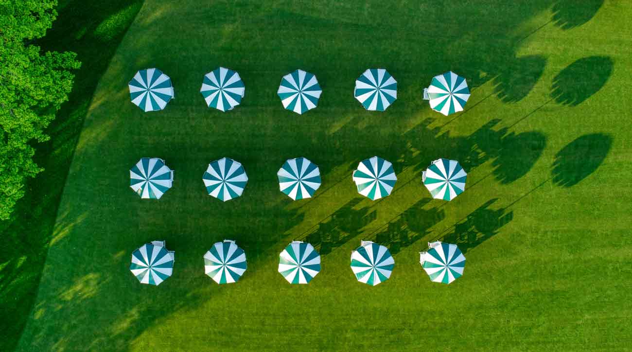 Three rows of five tables covered by green and white umbrellas. All perfectly spaced. 