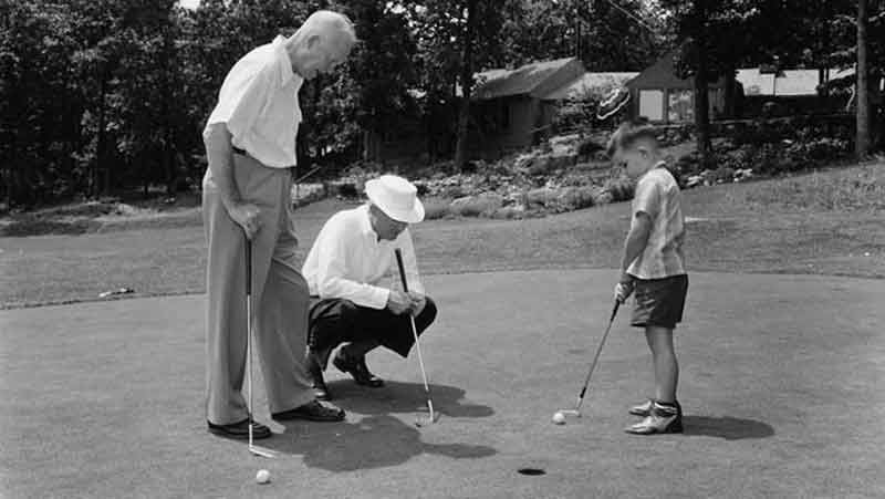 President Dwight Eisenhower watches grandson David putt at Camp David.