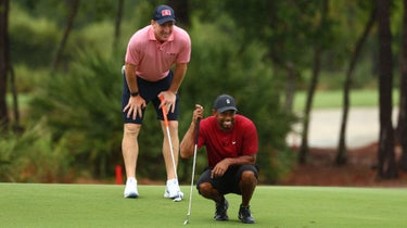 Tiger Woods and Peyton Manning line up a putt.