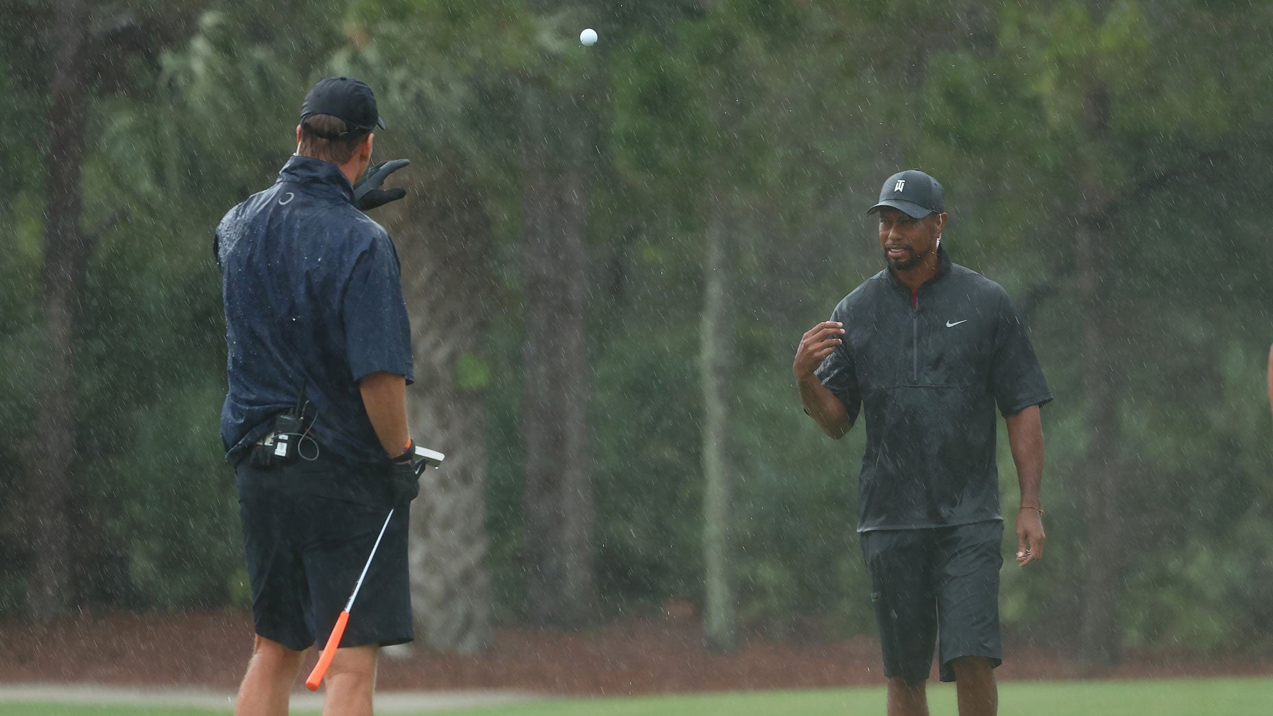Tiger Woods tosses a ball to partner Peyton Manning as Tom Brady looks on at Medalist Golf Club.