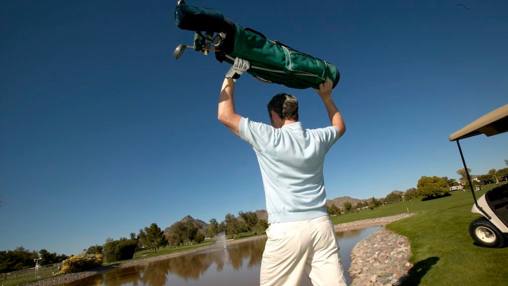 Man throwing golf cart into lake