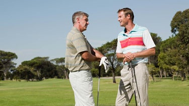 Two golfers talk on the golf course.