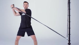 Man uses exercise band for rotational exercise.