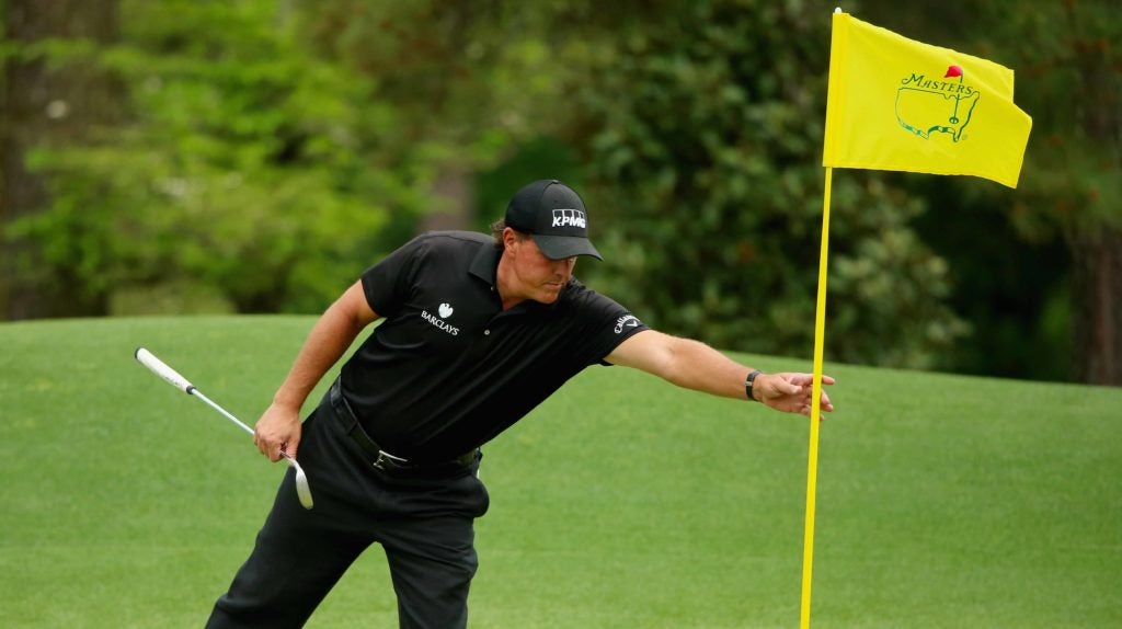 Phil Mickelson reaches for a flagstick