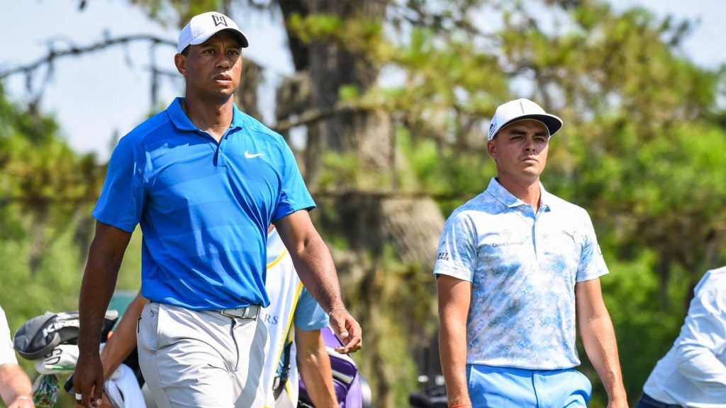 Tiger Woods and Rickie Fowler walk off the tee box.