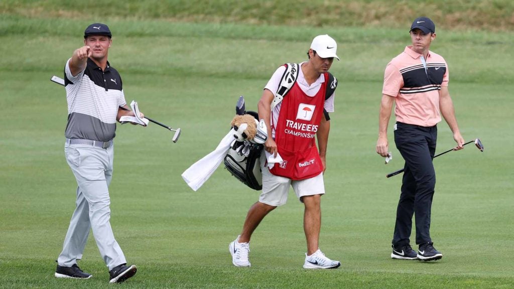Pro golfers Bryson DeChambeau and Rory McIlroy walk on golf course