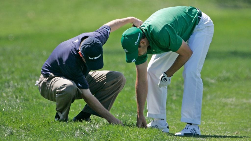 Two golfers look for golf balls.