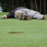 Golfer laying on the green.