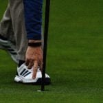 golfer picks ball from cup