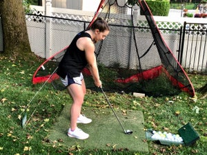 The author sets up to hit a golf ball into a net.
