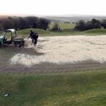 Sand being poured on golf greens.