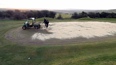 Sand being poured on golf greens.