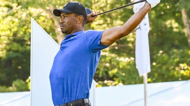 Tiger Woods stretches his back and shoulders before the round.