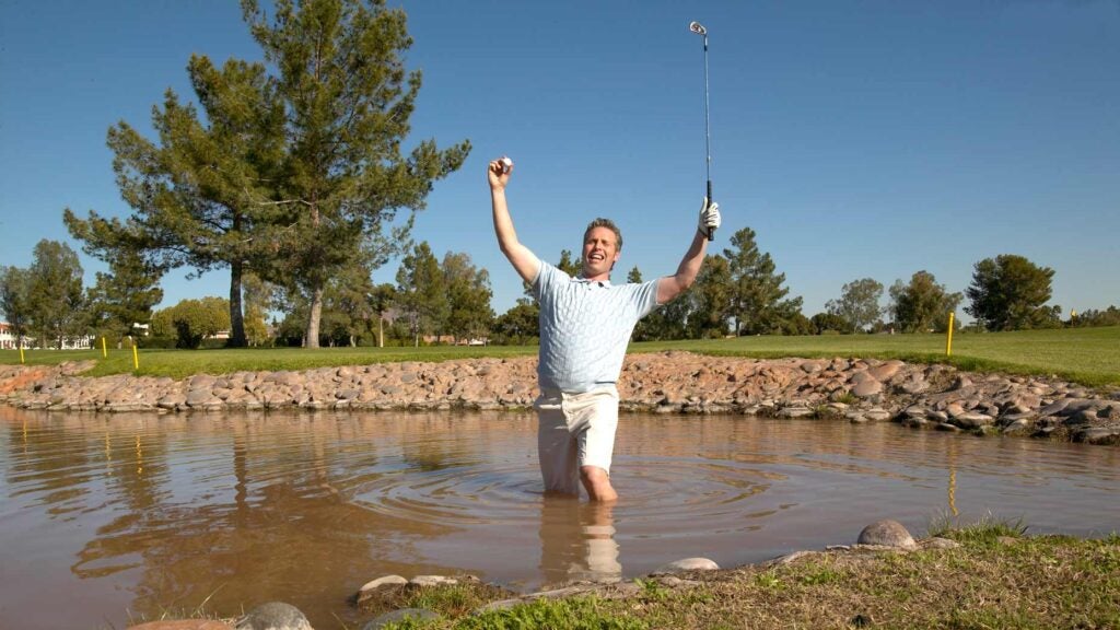 man swims in lake for golf ball
