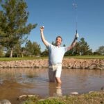 man swims in lake for golf ball