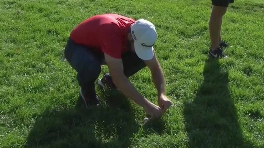 Matthew Wolff carefully attempts to remove a divot that was resting against his golf ball.