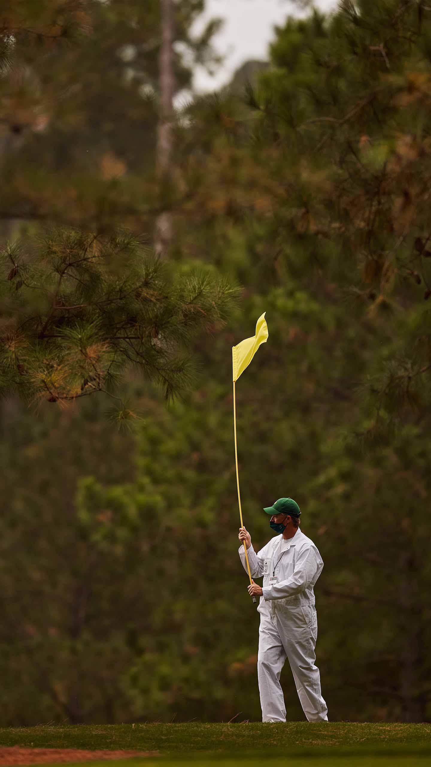 masters caddie holds flag on green