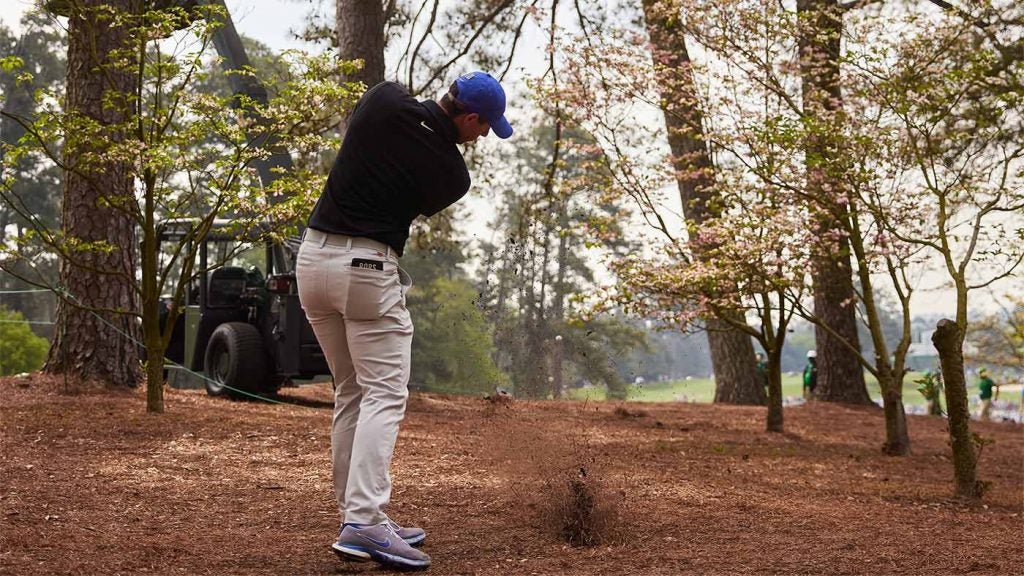 Rory McIlroy hits a ball out of the pinestraw.