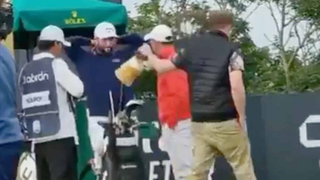 a fan takes a headcover from rory mcilroy's golf bag