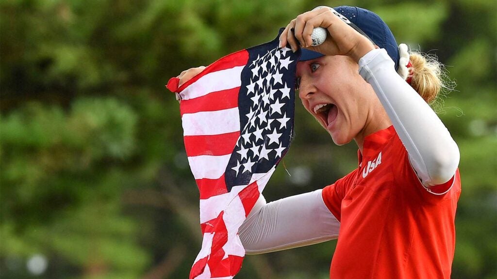 Nelly Korda holds up the american flag at the olympics.