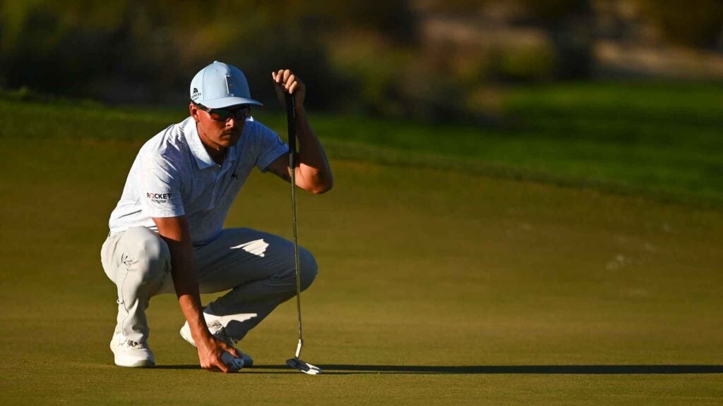 Rickie Fowler crouches over a putt