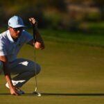 Rickie Fowler crouches over a putt