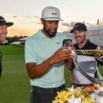Tony Finau FaceTimes with his family next to the Northern Trust trophy
