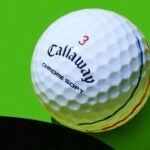 A Callaway Chrome Soft Triple Track golf ball against a green background