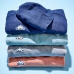 A stack of four Radmor Higgins golf hoodies against a baby blue background