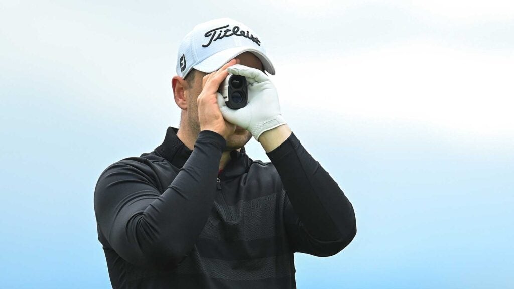 A golfer looks through a rangefinder.
