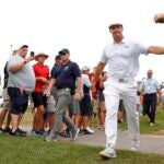 bryson dechambeau high fives fans while walking in between golf holes