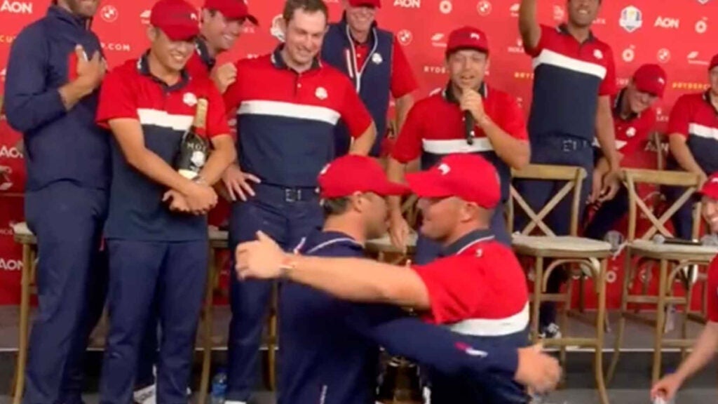 Bryson DeChambeau and Brooks Koepka hug in front of their Ryder Cup teammates following the U.S. victory